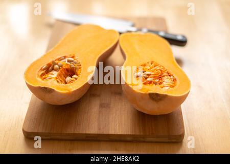 Courge musquée (Cucurbita moschata)-coupée en deux sur un foyer sélectif de planche à découper Banque D'Images