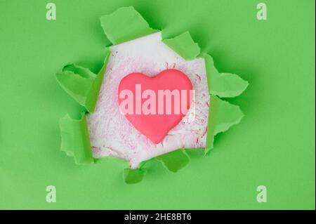 Le papier déchiré vert, au milieu, est couché Un coeur rose fait de Plasticine comme symbole pour les soins de santé Banque D'Images