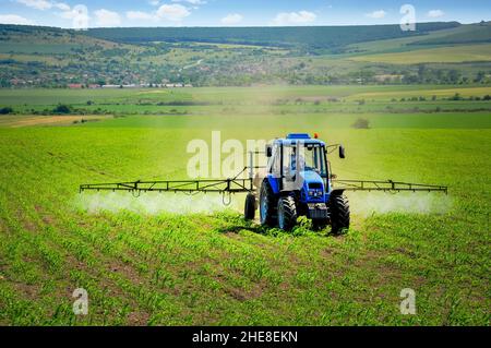 Tracteur agricole labourer et pulvériser sur terrain Banque D'Images