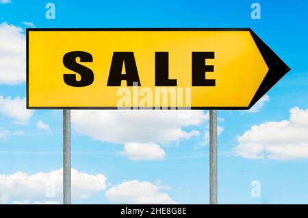 Signe de vente - panneau de route jaune avec flèche pointant vers la droite contre ciel bleu nuageux Banque D'Images
