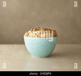 bol de caramel fouetté et de mousse au café dessert à la crème décoré de morceaux de chocolat sur une table de cuisine Banque D'Images