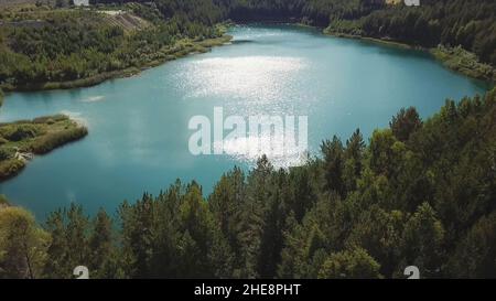 Vol au-dessus de l'eau azur du lac et de la forêt verte.Vue aérienne d'un paysage d'été à couper le souffle avec un beau lac turquoise entouré de verdure Banque D'Images