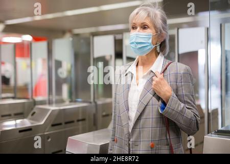 Femme âgée dans un masque à l'entrée de la station de métro Banque D'Images