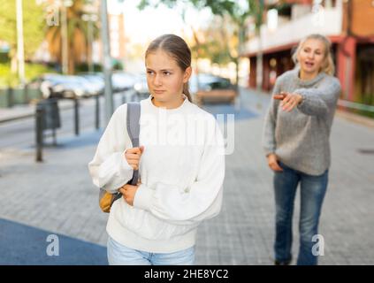 Une jeune fille agacée marchant dans la rue de la ville avec une mère inquiète qui la reproche Banque D'Images