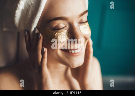 Portrait rapproché d'une femme avec une serviette sur la tête en prenant soin de sa peau avec des taches sous les yeux.Traitement de rajeunissement.Soin du visage.Santé Banque D'Images