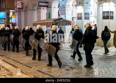 Rangées de la reconstitution hellénique de la police d'ordre marchent dans le centre-ville de Monastiraki district de nuit à Athènes, Grèce lors d'une manifestation Covid 19. Banque D'Images