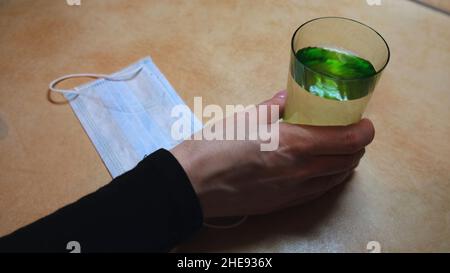 Quarantaine et Covid 19 thème de prévention.Gros plan de la femme qui prend des pilules et un verre d'eau de la table et puis de mettre sur le masque médical. Banque D'Images