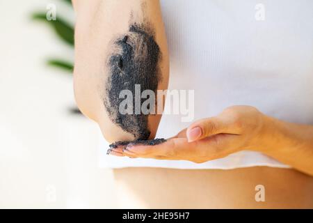 Jeune femme appliquant du grain de café moulu sur la peau Banque D'Images