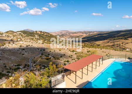 Vue sur la chaîne de montagnes de la Sierra del Pinar depuis le sommet de la piscine municipale El Tajo Grazalema, la piscine publique de Grazalema, en Espagne. Banque D'Images