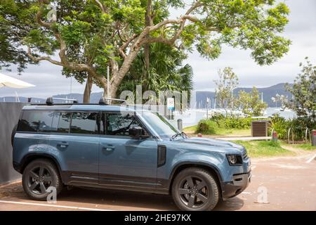 Nouveau véhicule tout-terrain Land Rover Defender 110 quatre portes en bleu Tasman, garé à côté d'une plage de Sydney, Nouvelle-Galles du Sud, Australie Banque D'Images