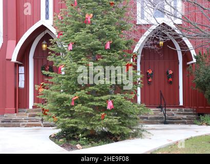 Deux portes rouges d'une église historique de Sonora, CA.Une couronne de Noël festive sur les portes et un arbre de Noël décoré accueillent la saison de l'Avent. Banque D'Images