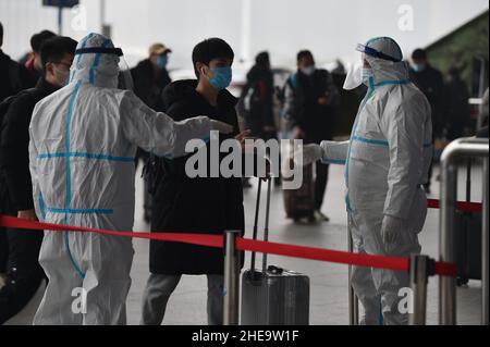 NANJING, CHINE - 10 JANVIER 2022 - les travailleurs de la prévention des épidémies vérifient les informations sanitaires des passagers un par un à l'entrée de Nanjing South Railw Banque D'Images