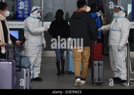 NANJING, CHINE - 10 JANVIER 2022 - les travailleurs de la prévention des épidémies vérifient les informations sanitaires des passagers un par un à l'entrée de Nanjing South Railw Banque D'Images