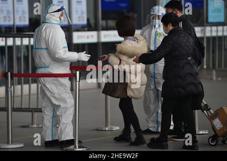 NANJING, CHINE - 10 JANVIER 2022 - les travailleurs de la prévention des épidémies vérifient les informations sanitaires des passagers un par un à l'entrée de Nanjing South Railw Banque D'Images