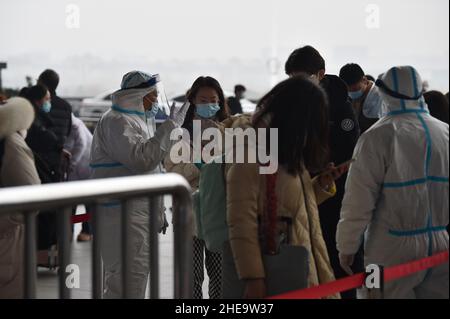 NANJING, CHINE - 10 JANVIER 2022 - les travailleurs de la prévention des épidémies vérifient les informations sanitaires des passagers un par un à l'entrée de Nanjing South Railw Banque D'Images