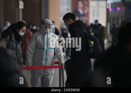 NANJING, CHINE - 10 JANVIER 2022 - les travailleurs de la prévention des épidémies vérifient les informations sanitaires des passagers un par un à l'entrée de Nanjing South Railw Banque D'Images