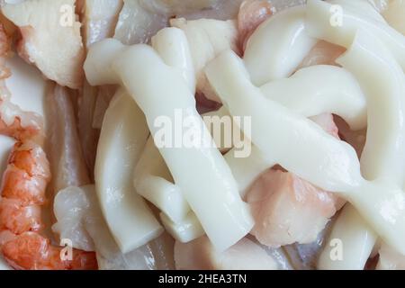 Gros plan sur des rondelles de calmar fraîches sur du merlu, du monkfish et des crevettes fraîches.Nourriture saine et poisson. Banque D'Images