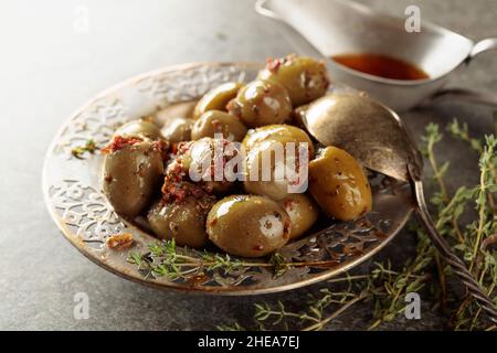 Olives vertes épicées à l'huile d'olive dans un ancien bol en métal.Bol avec olives et brindilles de thym sur une table en pierre. Banque D'Images