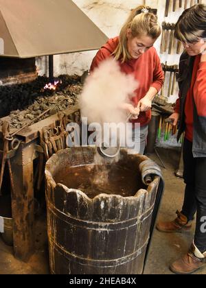 16 décembre 2021, Saxe, Leipzig: Les deux filles de Kunstschmied Althammer, maître métallurgiste et chef actuel de la forge, Elisabeth Althammer-Kluge (r) et graphiste et compagnon de métal Claudia Süßmeyer se tiennent près du feu de forge tout en travaillant sur un bar pour une porte.Althammer, qui a fondé sa forge artistique il y a 45 ans, est ravi que ses deux filles aient pris en charge l'entreprise de l'artisan et qu'il puisse lui-même fournir des conseils basés sur ses nombreuses années d'expérience.(À dpa KORR: 'L'artisanat reste dans la famille - les filles prennent le contrôle de la forge d'art') photo: Waltraud Grubitzsch/dpa-Zen Banque D'Images