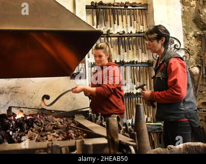 16 décembre 2021, Saxe, Leipzig: Les deux filles de Kunstschmied Althammer, maître métallurgiste et chef actuel de la forge, Elisabeth Althammer-Kluge (r) et dessinatrice de métal et compagnon de forgeron Claudia Süßmeyer travaillent sur un bar pour une porte à l'incendie de la forge.Althammer, qui a fondé sa forge artistique il y a 45 ans, est ravi que ses deux filles aient pris en charge l'entreprise de l'artisan et qu'il puisse lui-même fournir des conseils basés sur ses nombreuses années d'expérience.(À dpa KORR: 'L'artisanat reste dans la famille - les filles prennent le contrôle de la forge d'art') photo: Waltraud Grubitzsch/dpa-Zentralbild Banque D'Images