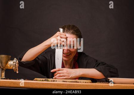 Main de fille avec un couteau coupant des oignons sur une planche en bois. Banque D'Images