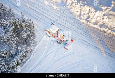 Déneigement avec tracteur rouge sur la route.SUNY, hiver, vue de dessus de Drone.Antenne.Vue de dessus. Banque D'Images