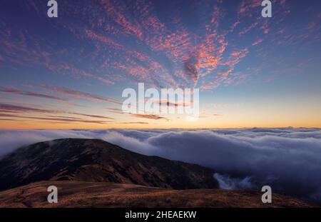 Fabuleux coucher de soleil dans les montagnes au-dessus des nuages.Vue aérienne d'un paysage de montagne spectaculaire au crépuscule avec brouillard et lumière douce. Banque D'Images