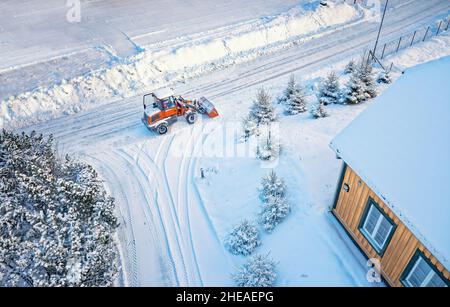 Déneigement avec tracteur rouge sur la route.SUNY, hiver, vue de dessus de Drone.Antenne.Vue de dessus. Banque D'Images