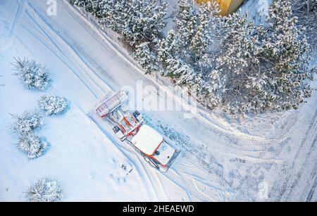 Déneigement avec tracteur rouge sur la route.SUNY, hiver, vue de dessus de Drone.Antenne.Vue de dessus. Banque D'Images