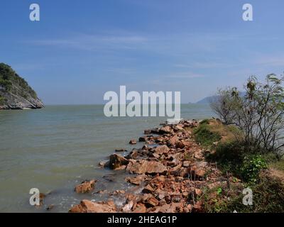 Récif rocheux et pierre dans l'eau verte de la mer avec montagne et île en arrière-plan, plage avec ciel bleu et nuage blanc à Khao Sam Roi Yot Banque D'Images