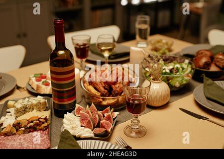 Gros plan d'une bouteille de vin rouge avec dinde et hors-d'œuvre servis sur la table à manger pour les vacances Banque D'Images