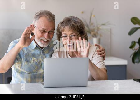 Des grands-parents heureux d'âge moyen tiennent une conversation par appel vidéo. Banque D'Images