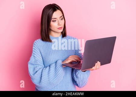 Portrait d'une fille attirante et spécialisée utilisant l'ordinateur portable dactylographiant le Web d'apprentissage isolé sur fond rose pastel couleur Banque D'Images