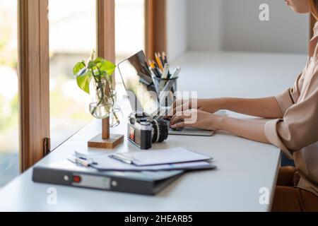 Jeune femme freelance dactylographiant sur clavier sur ordinateur portable pour travailler au bureau moderne Banque D'Images