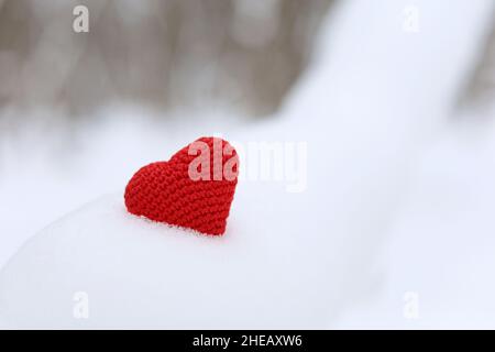 Coeur tricoté rouge dans la neige sur fond de forêt d'hiver.Carte de Saint-Valentin, amour romantique Banque D'Images