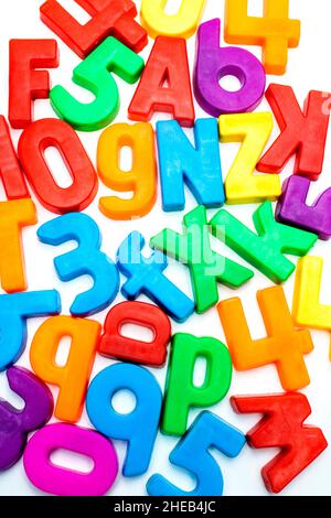Alphabet coloré et aimants de nombre dispersés sur une surface blanche, favorisant l'apprentissage de la petite enfance et les activités de jeu Banque D'Images