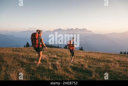 Un jeune couple marche dans la lumière du soir au-dessus d'une prairie alpine idyllique, Salzbourg, Autriche, Europe Banque D'Images