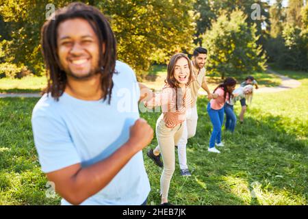 Les jeunes rient et se tiennent les mains pendant un exercice de renforcement d'équipe en été Banque D'Images