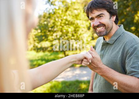 Les jeunes hommes et les jeunes femmes se saluent les uns les autres avec une bosse de poing pour la motivation et la coopération Banque D'Images