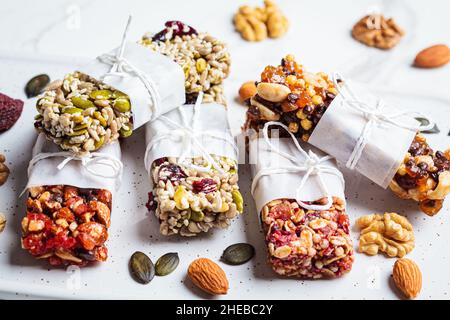 Barres de granola d'énergie avec différentes graines, noix et fruits secs et baies sur un fond de marbre blanc.Concept d'en-cas sain. Banque D'Images