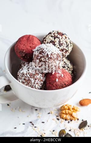 Dessert végétalien cru.Boules d'énergie.Truffes à base de noix, de graines, de cacao, de dattes et de diverses poudres de super-aliments, fond en marbre blanc. Banque D'Images