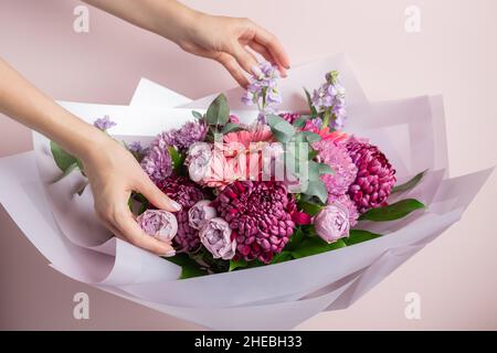Femme avec bouquet de fleurs mixtes sur fond rose Banque D'Images