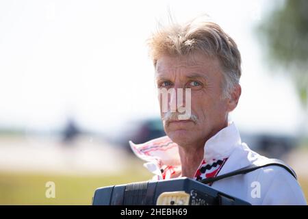 Une fête de l'humour.Un bélarussien slave ou ukrainien dans un chapeau de paille joue l'accordéon. Banque D'Images