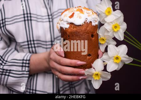 Gâteau de Pâques dans les mains et les fleurs des femmes. Décorations et gâteries traditionnelles. Banque D'Images