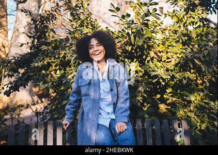 Mode Street style portrait d'attrayant jeune beauté naturelle afro-américaine avec cheveux afro en bleu manteau et jeans posant à l'extérieur.Les touristes se réjouissant de faire des promenades en ville Banque D'Images