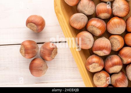 Plusieurs noisettes non pelées avec plateau de bambou sur une table en bois, vue rapprochée du dessus. Banque D'Images