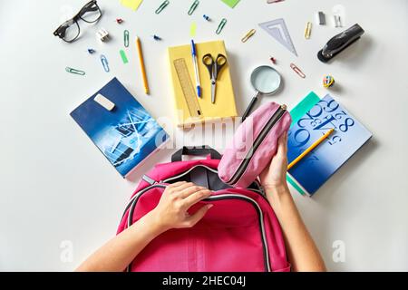 mains avec sac à dos, livres et fournitures scolaires Banque D'Images
