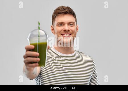 homme buvant du smoothie vert dans une tasse jetable Banque D'Images