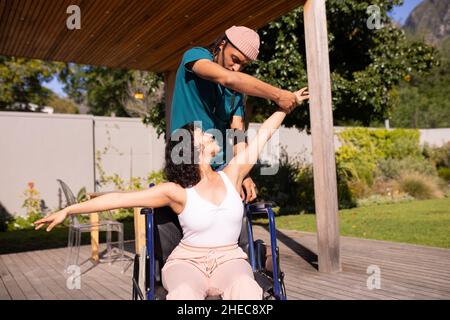 Femme afro-américaine handicapée en fauteuil roulant dansant avec son mari à l'extérieur Banque D'Images