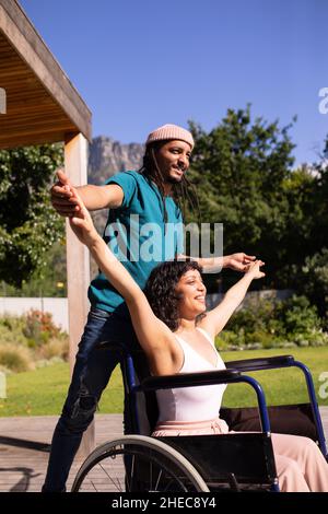 Femme afro-américaine handicapée en fauteuil roulant dansant avec son mari à l'extérieur Banque D'Images